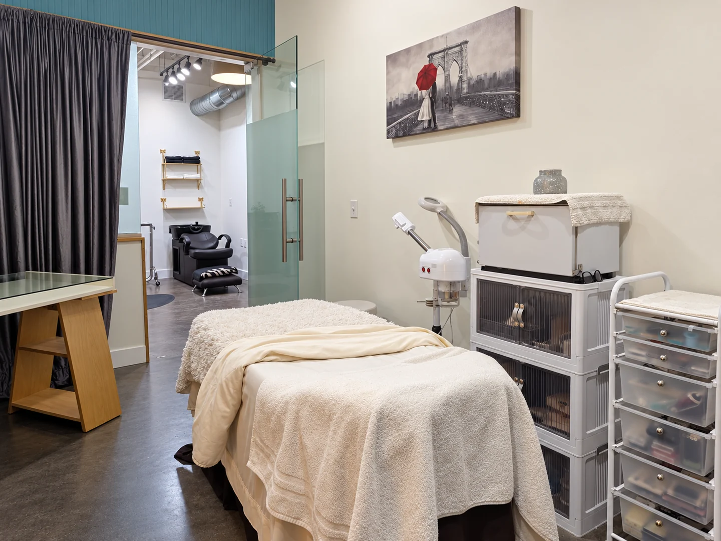 Facial treatment room with a cream-covered bed, steamer and skin care equipment at Elemntal Wellness