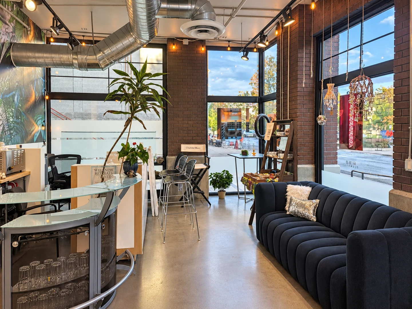 Reception lounge with a curved glass counter, navy sofa and large windows at Elemntal Wellness